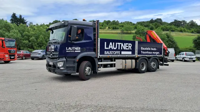 Blauer Kran-LKW mit Fahrzeugbeschriftung an Kabine und Pritsche